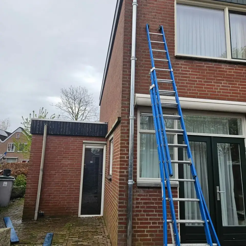 Montage van een zinken regenpijp langs een woning