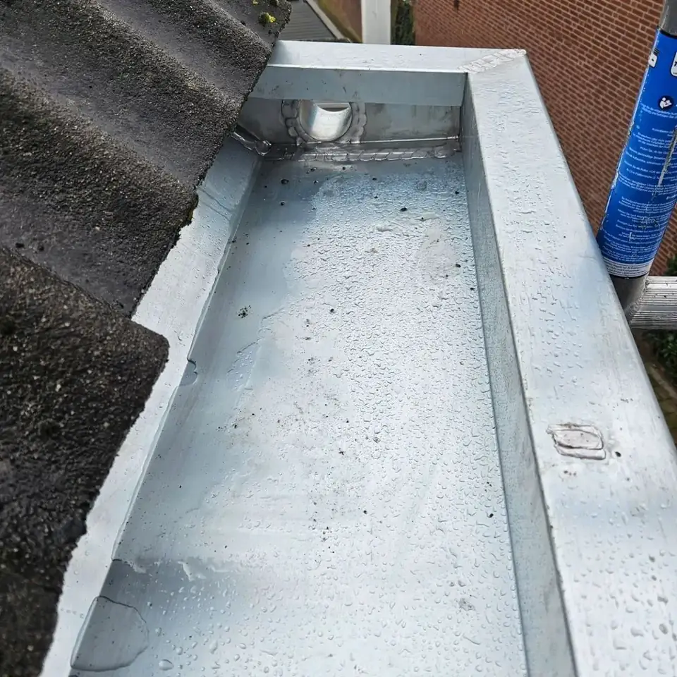 Nieuw gemonteerde zinken dakgoot langs een dakrand